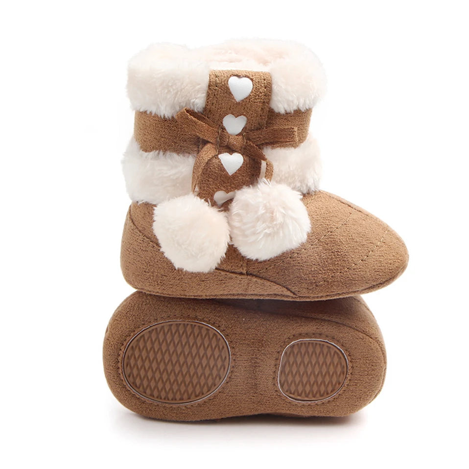 Heart slippers for babies with plush faux fur lining, heart details, and pom poms