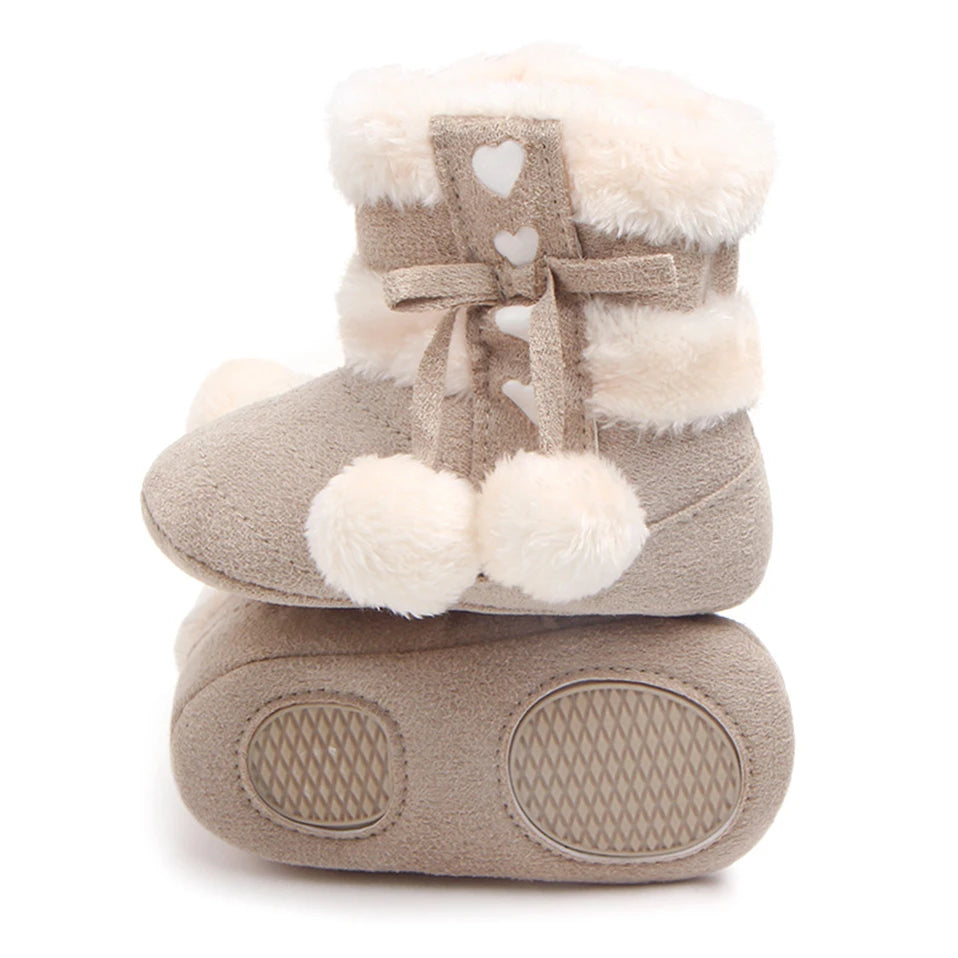 Heart Slipper Boots for babies with plush lining, heart details and fluffy pom poms, perfect for keeping little feet warm.