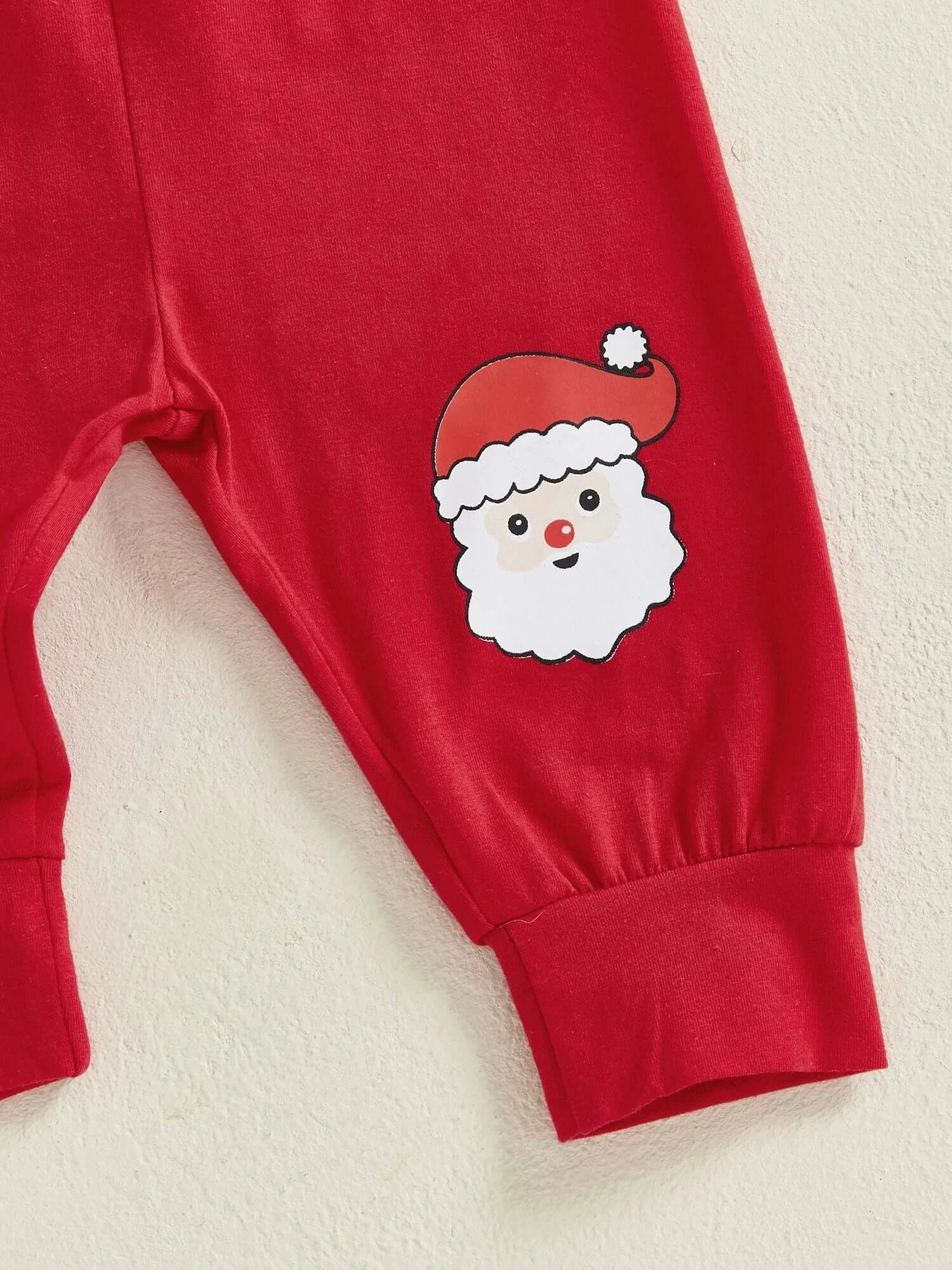 Close-up of red baby pants featuring a playful Santa face graphic, perfect for festive celebrations.