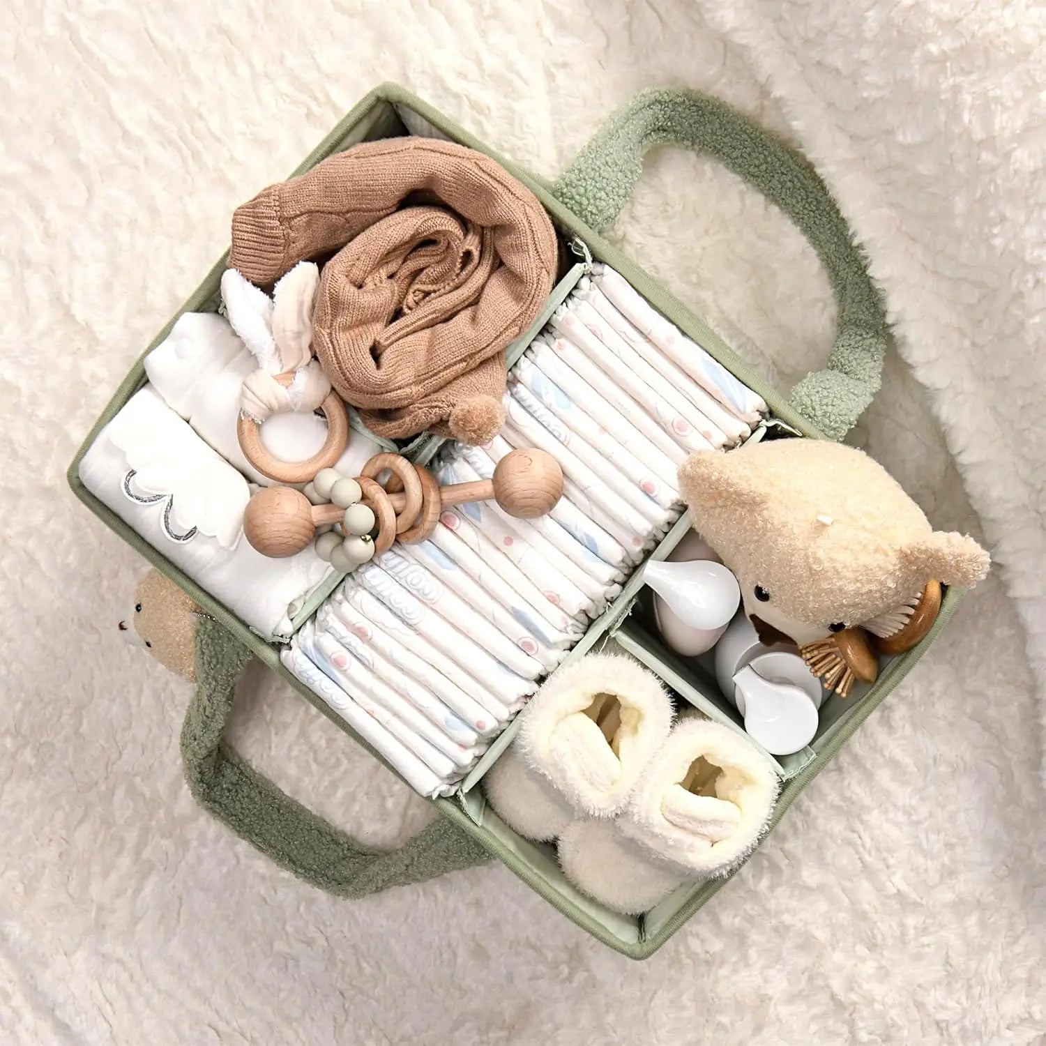 Plush Nappy Caddy in green teddy fabric, filled with baby essentials like nappies, blankets, toys, and booties.