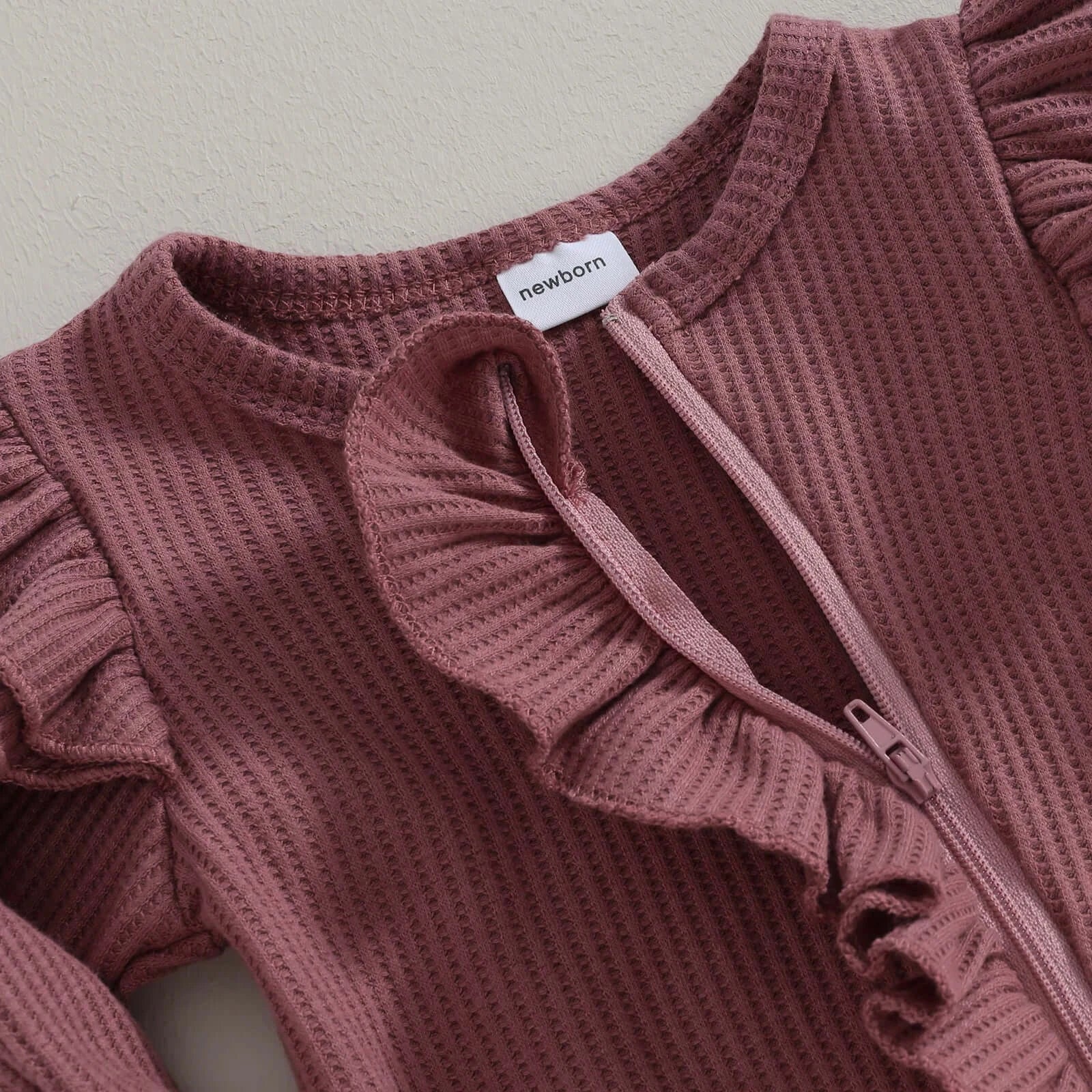 Whitney Long-Sleeve Ruffle Newborn Baby Onesie with zip closure in plum, closeup showing the beautiful waffle fabric.