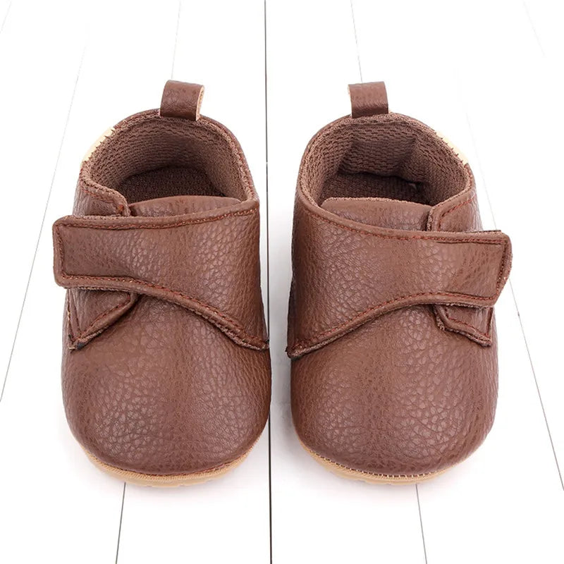 Brown vegan leather baby shoes for pre-walkers, offering style and comfort with a flexible rubber sole.