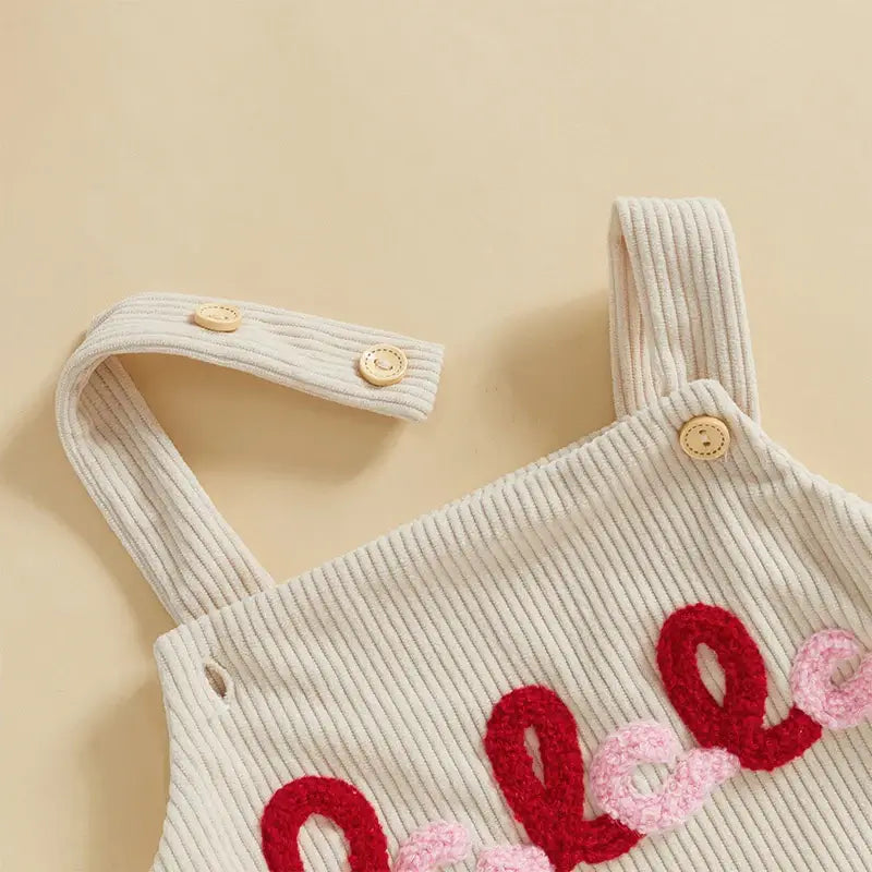 Close-up of the Fa La La Christmas romper showing the soft corduroy fabric and cheerful embroidery.