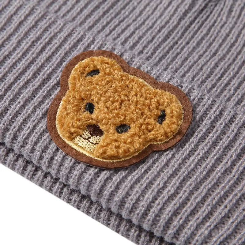 Closeup of teddy bear embroidery on grey ribbed knit baby beanie