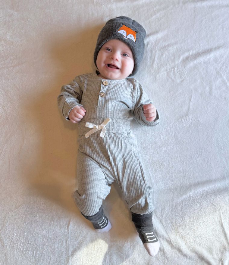 Smiling baby boy wearing ribbed bodysuit and pants set from Lulu Babe, in grey