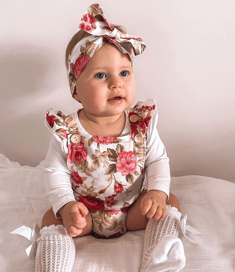 Baby girl wearing a vintage floral romper with matching headband - perfect for holiday photos