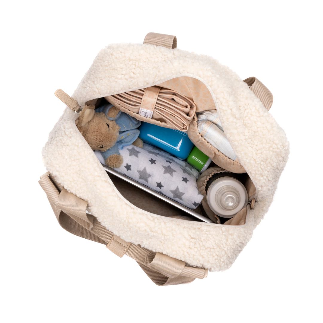 Inside view of Babymel Teddy Cream Nappy Backpack showing baby essentials, including a blanket, bottles, and a teddy bear.