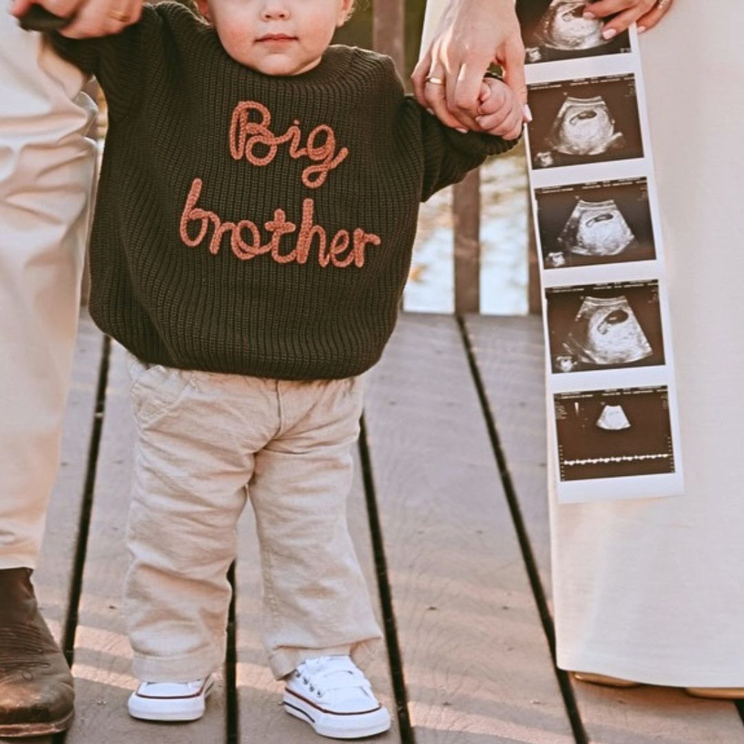 Toddler wearing big brother jumper in pregnancy announcement photoshoot