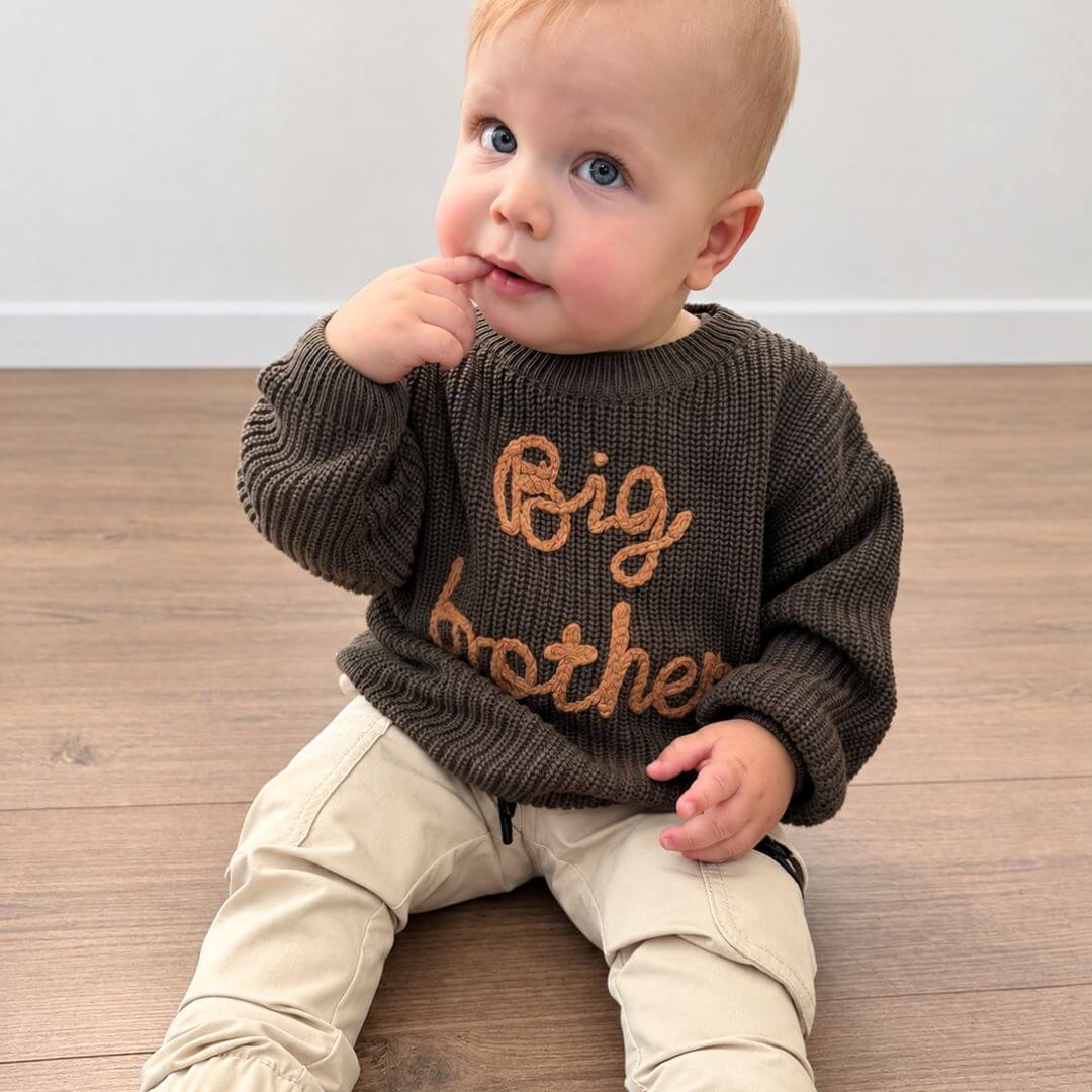 Toddler boy wearing a dark green Big Brother jumper from Lulu Babe