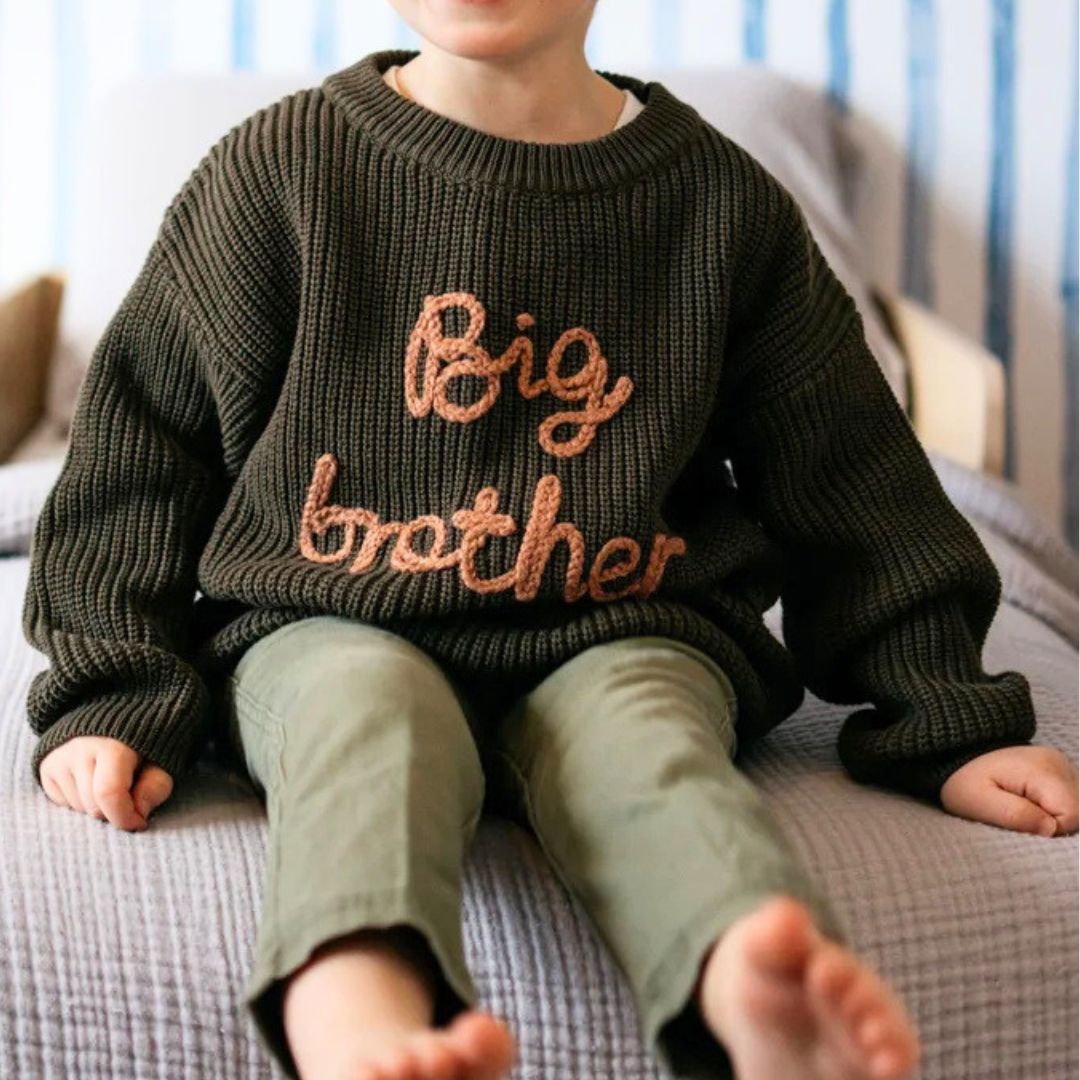 Boy wearing big brother jumper in green