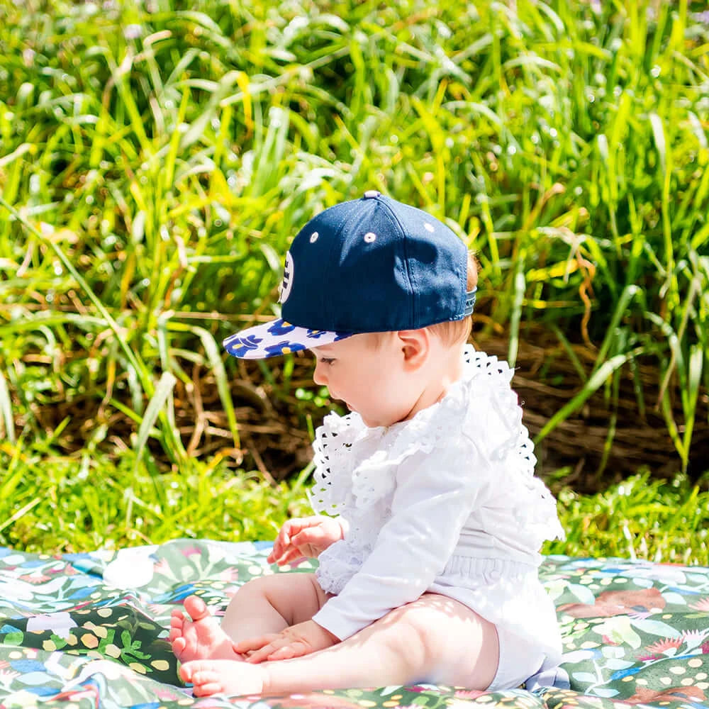 Baby girl wearing purple floral cap from Little Renegade Company