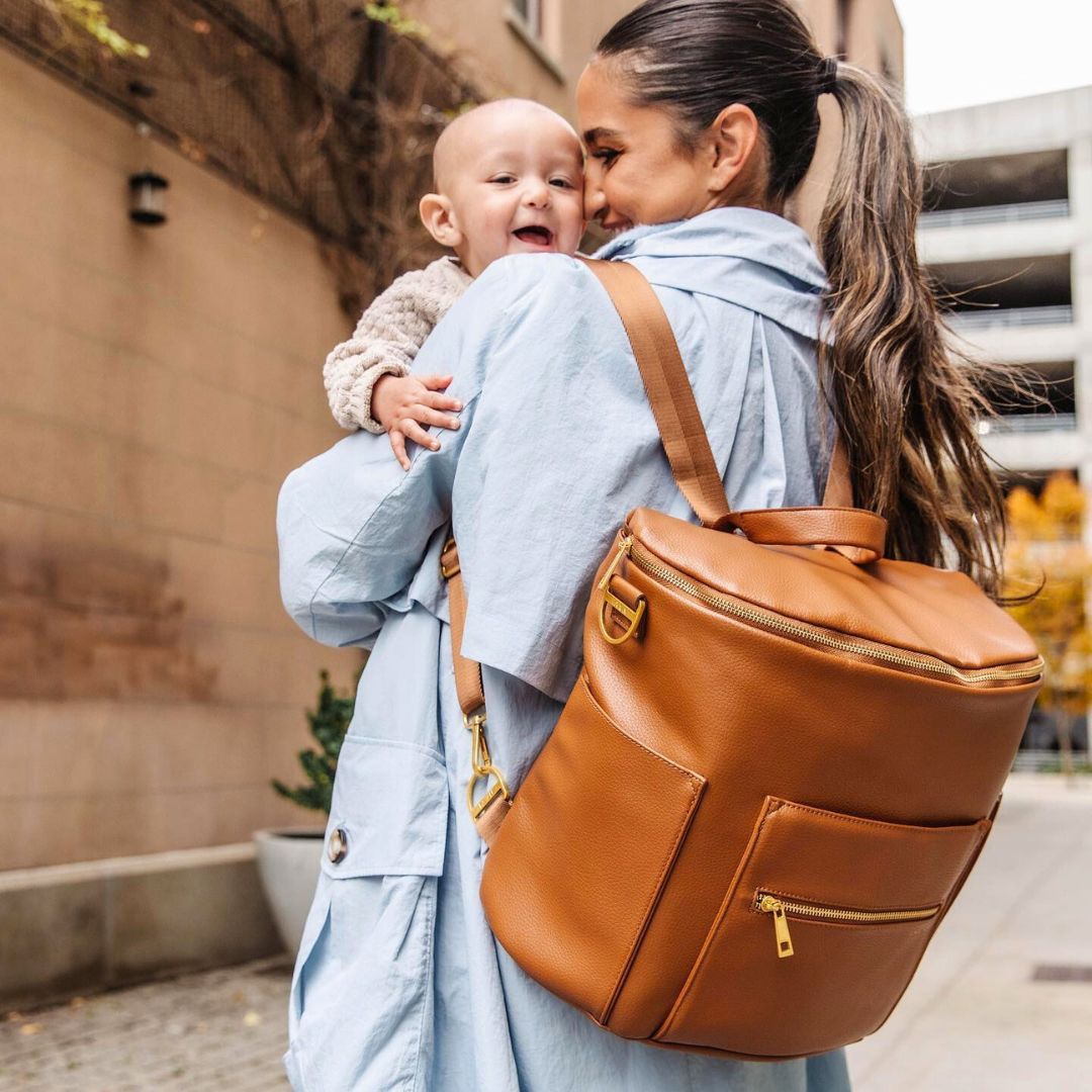Brooklyn nappy bag in tan vegan leather - styled by a mum carrying a baby (also in black)