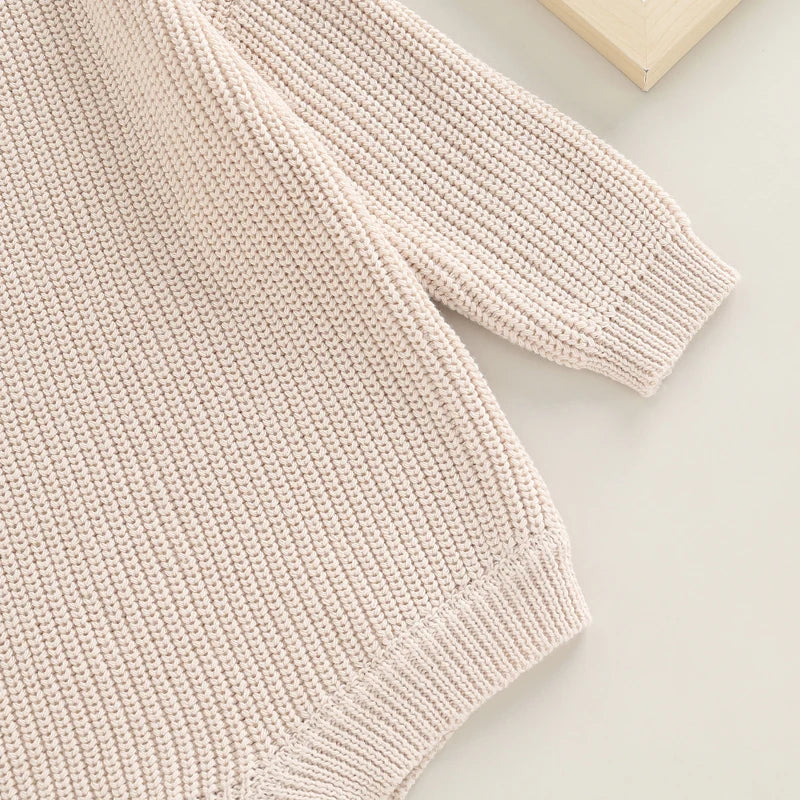 Close-up of textured long-sleeve knit winter romper in oatmeal