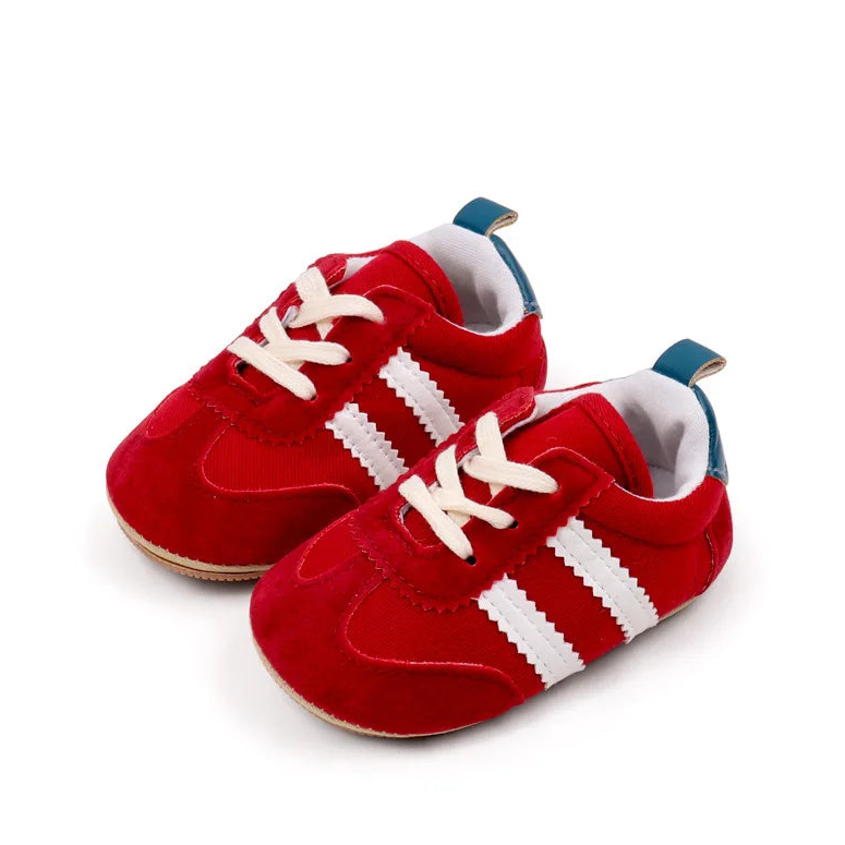 Classic red baby sneakers with white stripes, offering sporty style and comfort for tiny feet aged 0-18 months.