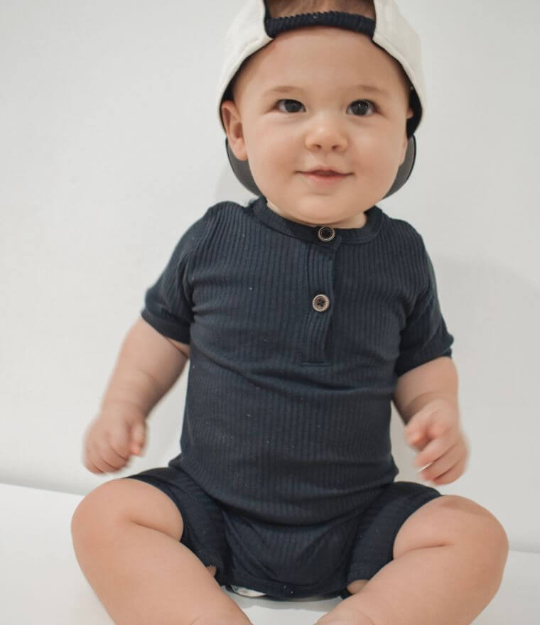 Smiling baby boy wearing short sleeve ribbed romper in navy