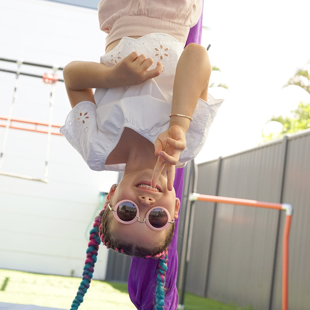 Girl wearing round pink retro sunglasses with UV400 lenses