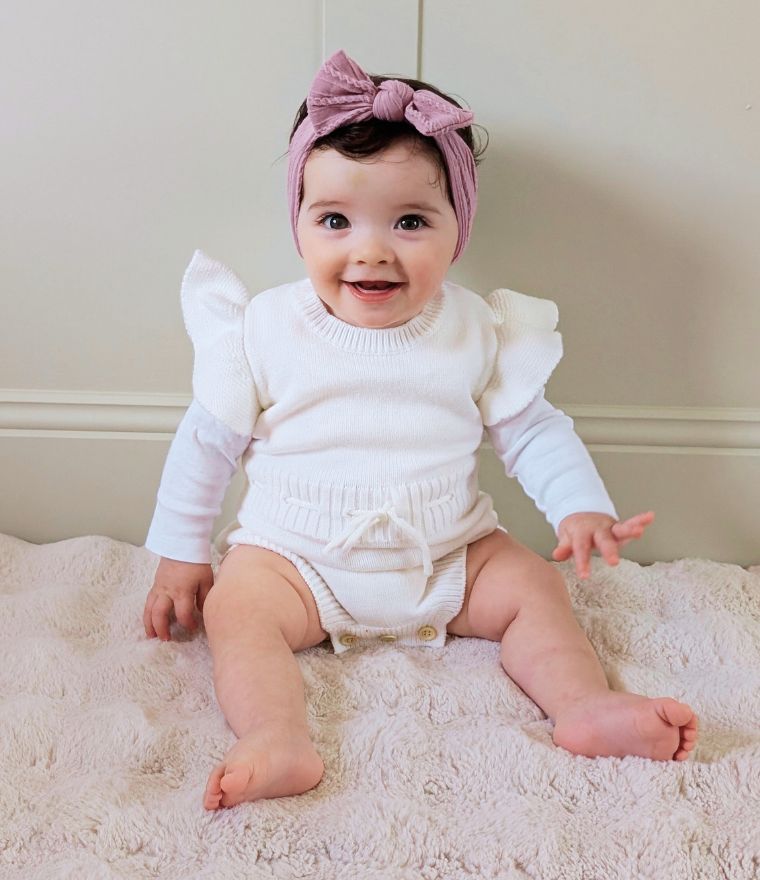 Baby girl wearing knit ruffle romper in white