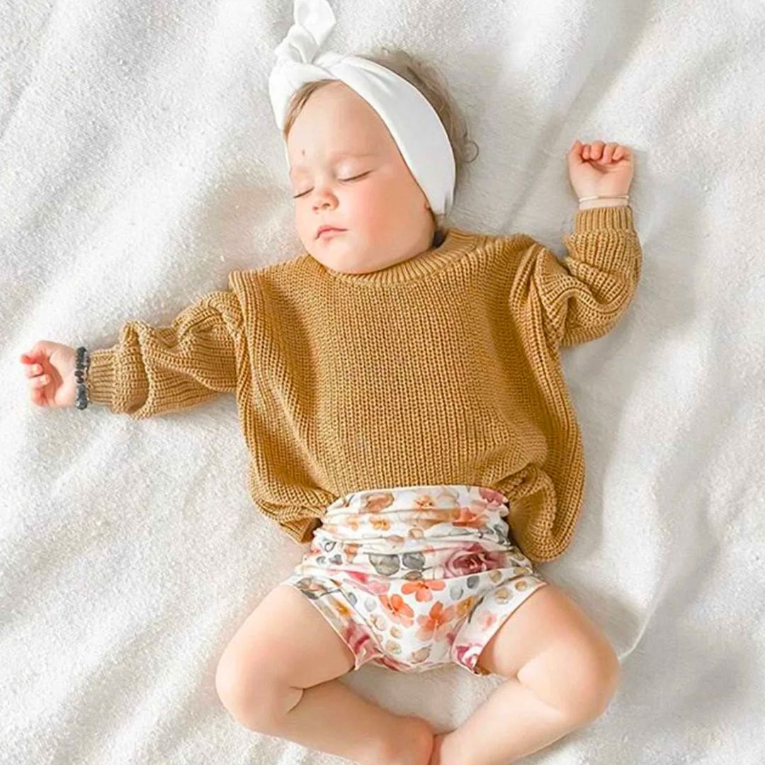 Sleeping girl wearing mustard knitted baby romper