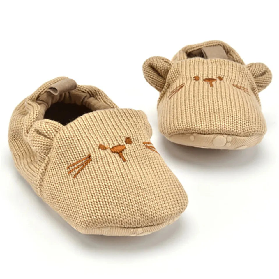 Knitted cat baby booties in tan with 3D ears, embroidered whiskers, and slip-on design for cosy little toes.