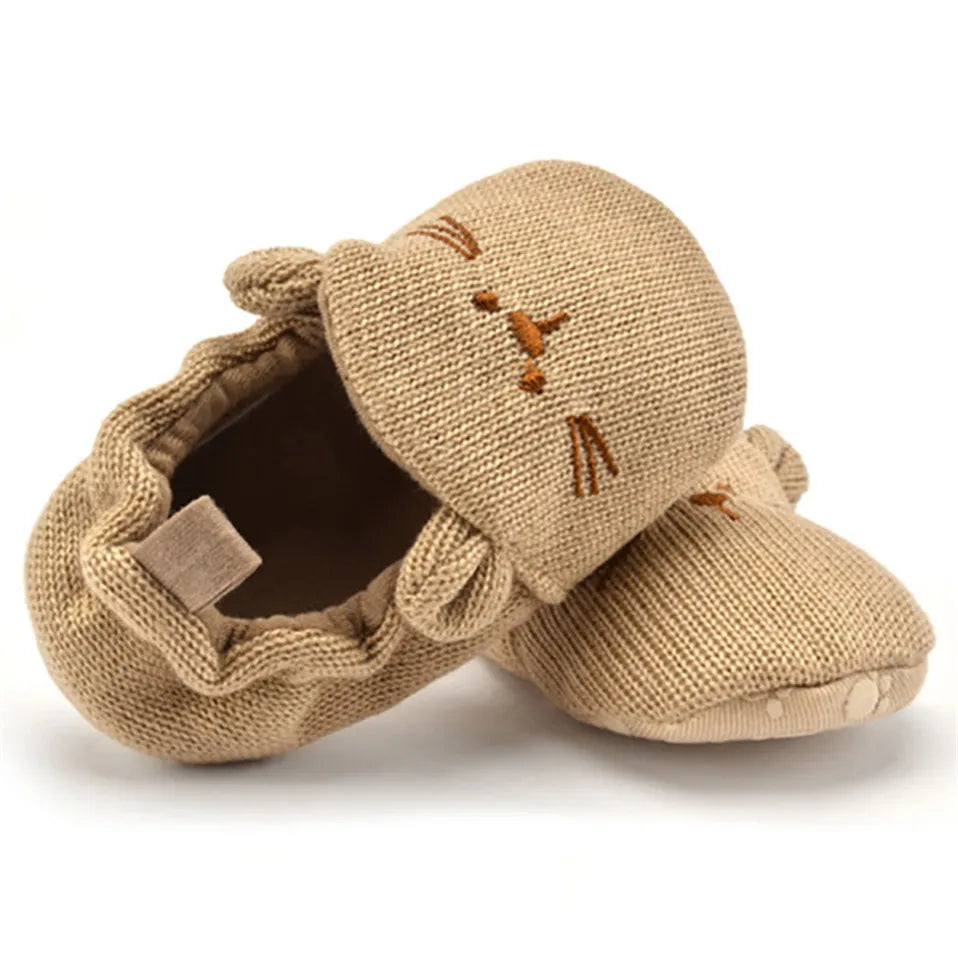 Adorable tan knitted cat baby booties with 3D ears and embroidered details, perfect for keeping little toes snug.