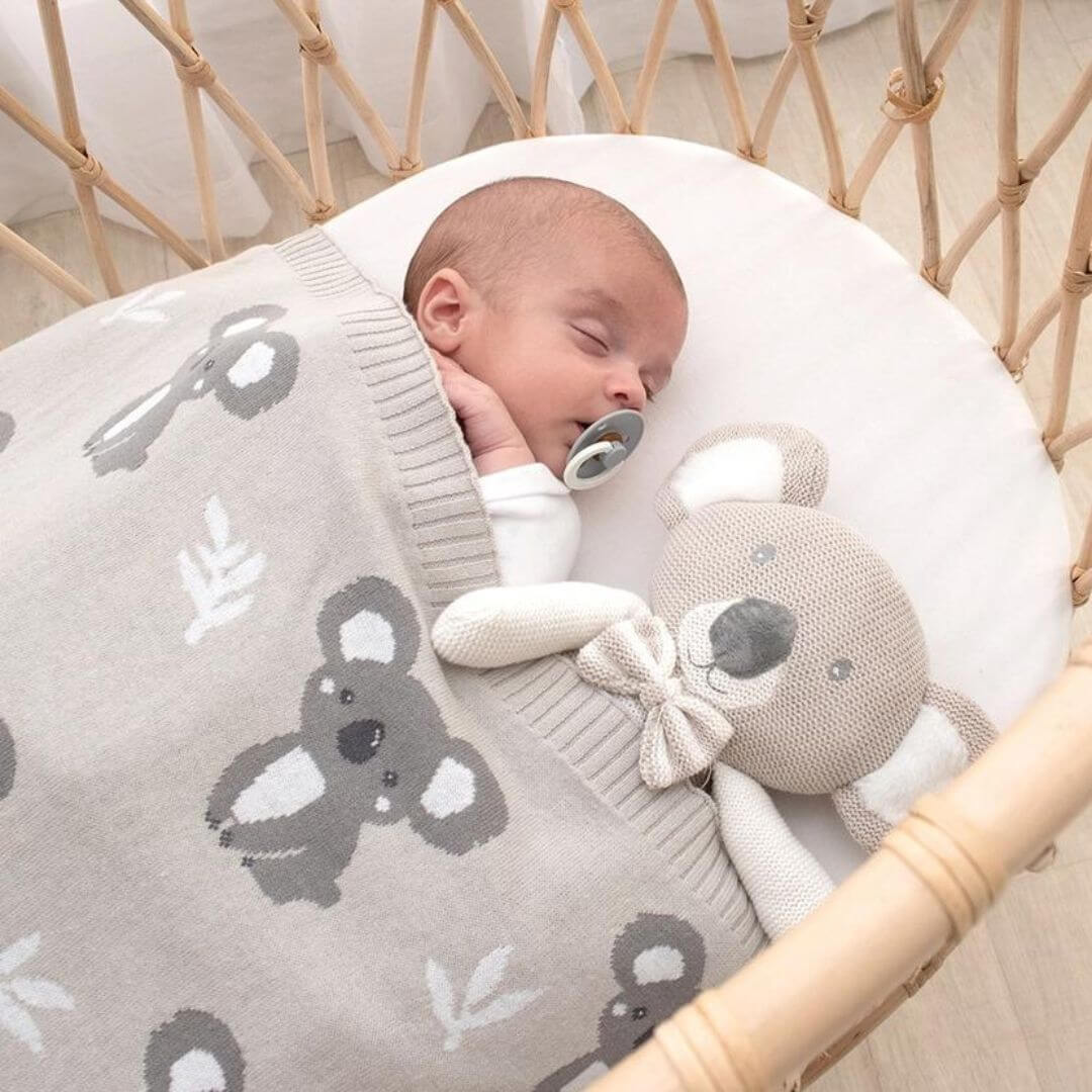 Infant sleeping soundly wrapped in a grey koala baby blanket made of 100% cotton knit