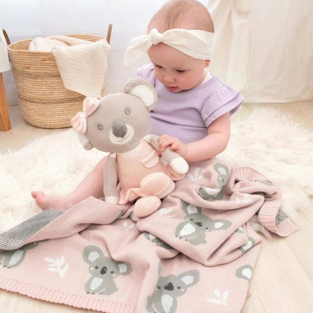 Baby cuddling with a koala plush toy on a soft pink koala baby blanket