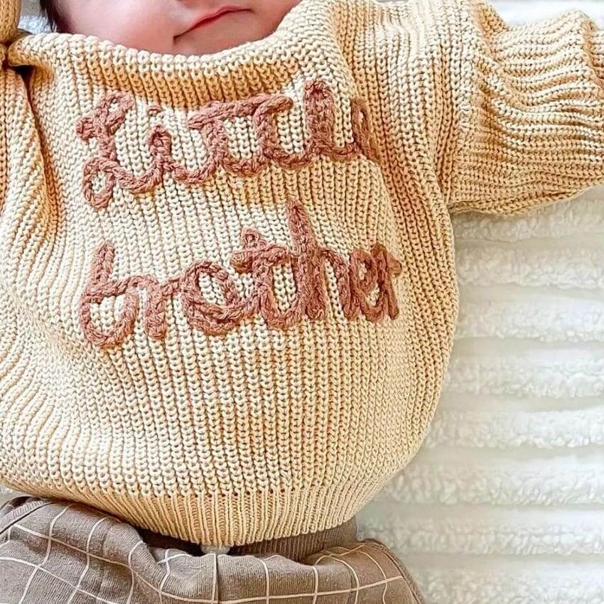 Lifestyle photo of baby boy wearing a Little Brother jumper in beige