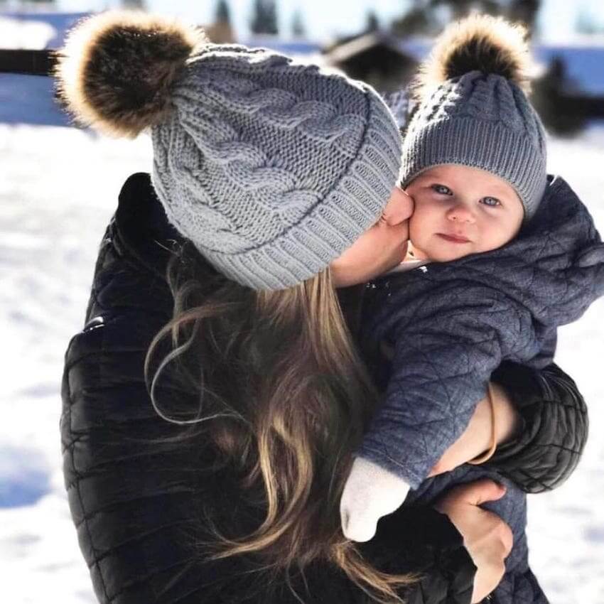 Mum and baby wearing matching grey cable-knit beanies
