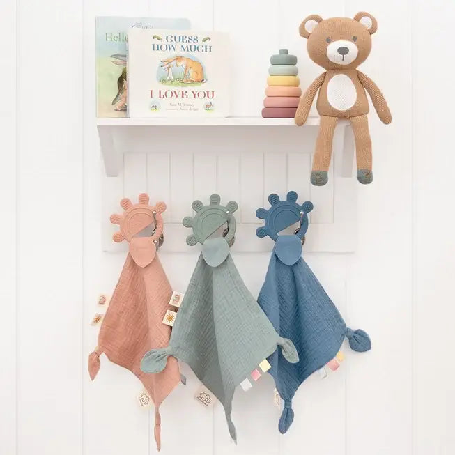 Personalised silicone teethers on a nursery shelf - in rose, sage and steel blue