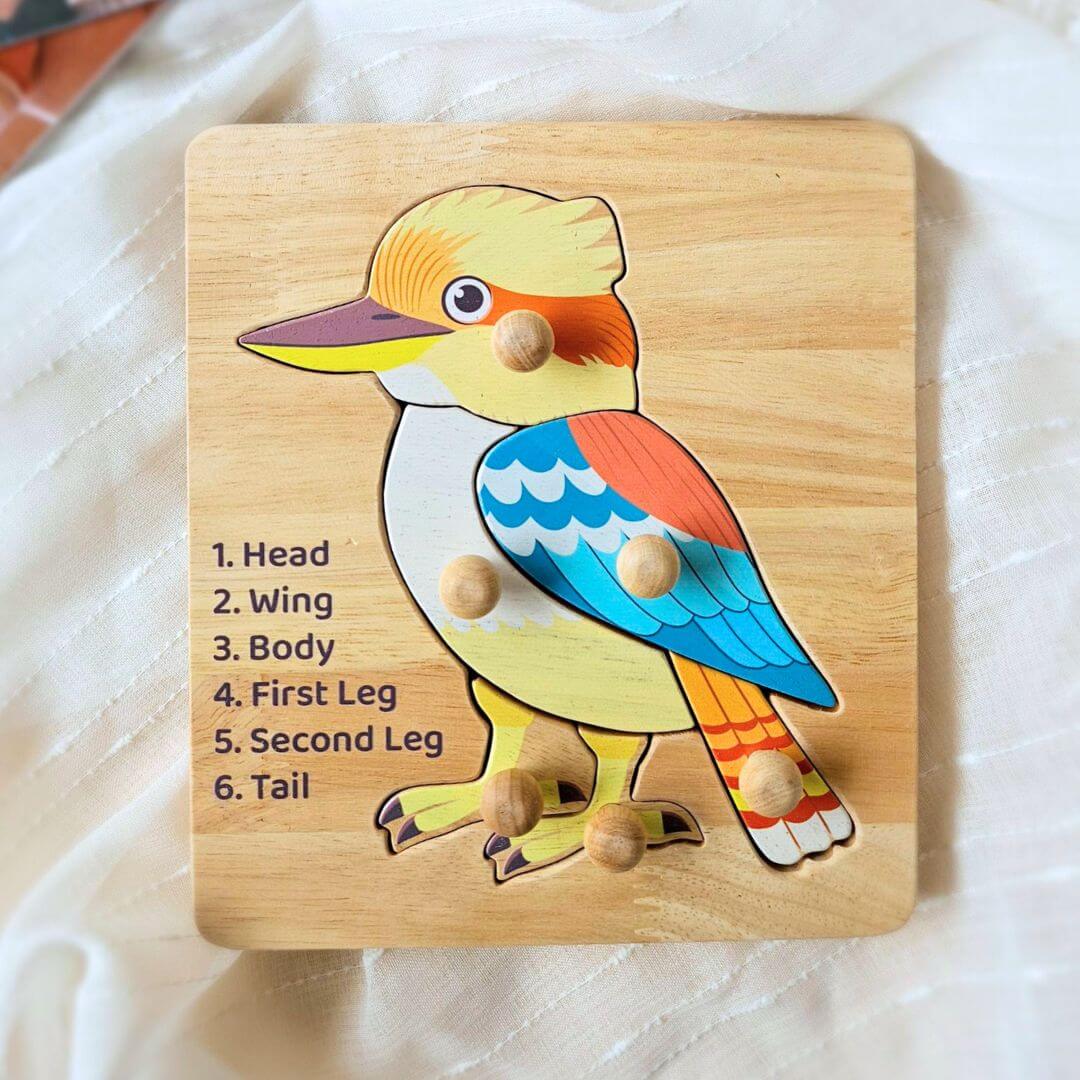 Wooden kookaburra knob puzzle with a blue wing and six knobbed pieces, labelled head to tail