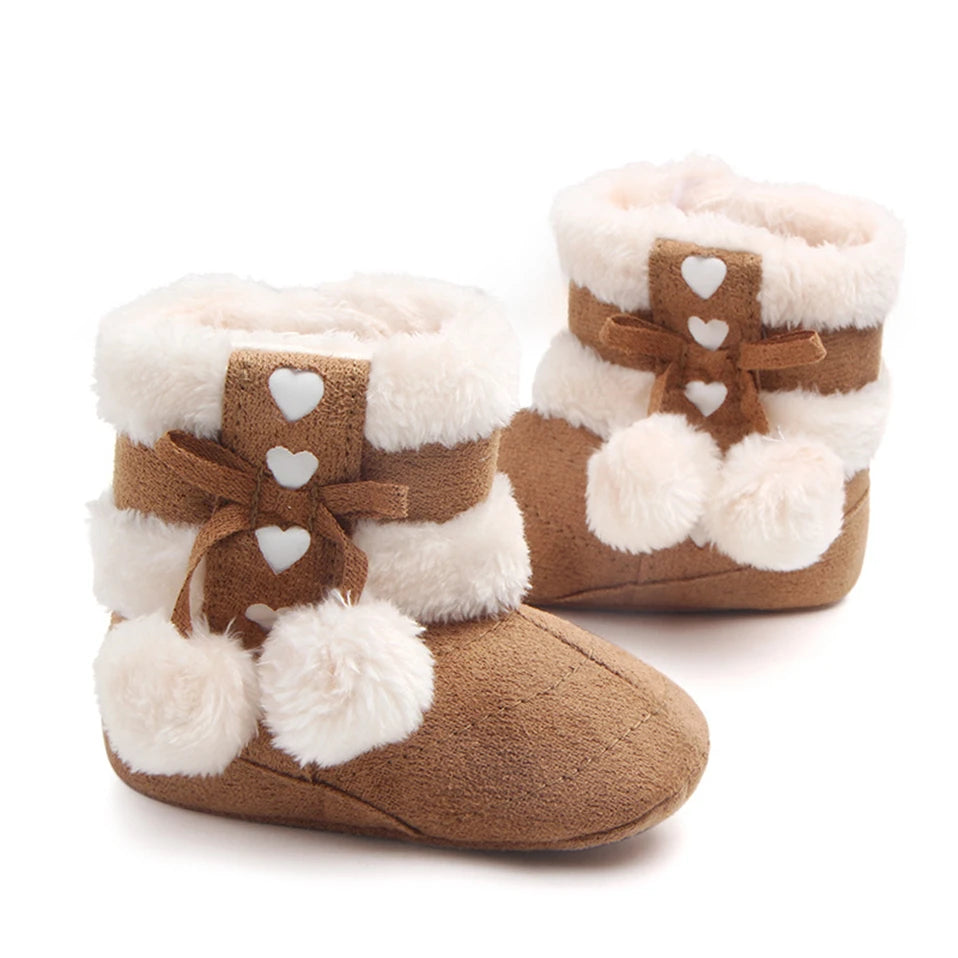 Soft brown Heart Slipper Boots for babies with plush lining, heart details, and pom poms, ideal for winter warmth.