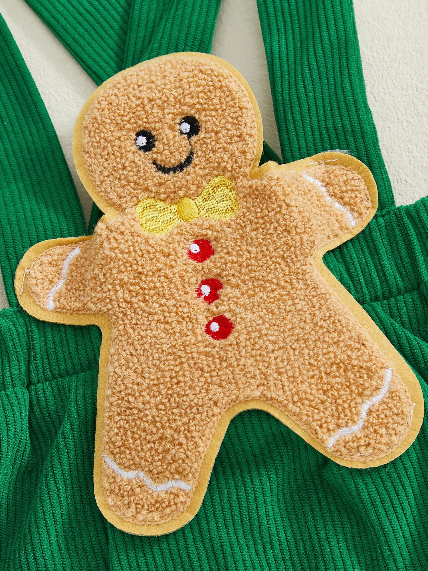 Close-up of gingerbread man appliqué on green corduroy romper, perfect for a festive Christmas baby outfit.