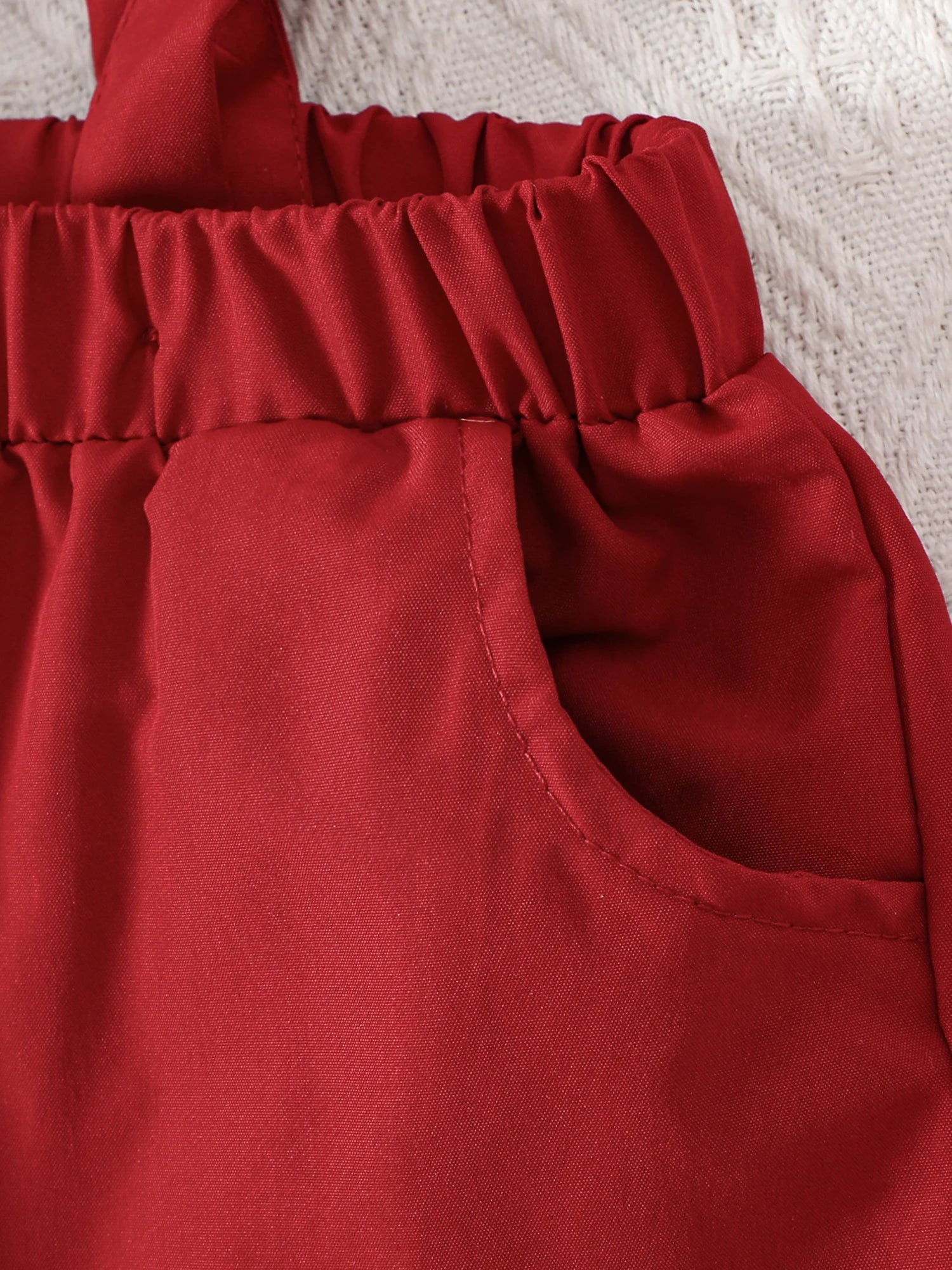 Close-up of red shorts with an elastic waist, perfect for a baby boy Christmas outfit featuring suspenders.