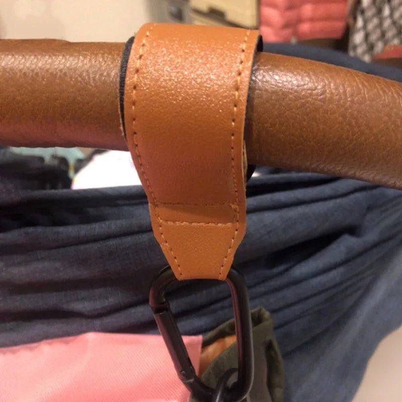 Universal Pram Clips attached to pram handle, featuring premium vegan leather and strong velcro straps for universal fit