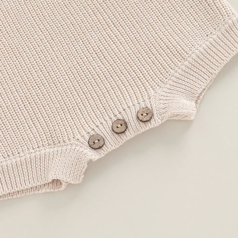 Close-up of the button details on our cosy chunky knit baby romper in sand