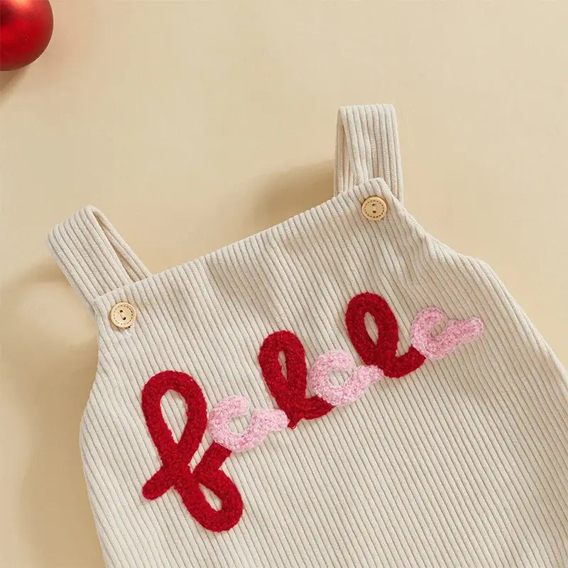 Close-up of Fa La La Christmas romper in cream corduroy with embroidered red and pink text, perfect for festive baby outfits.