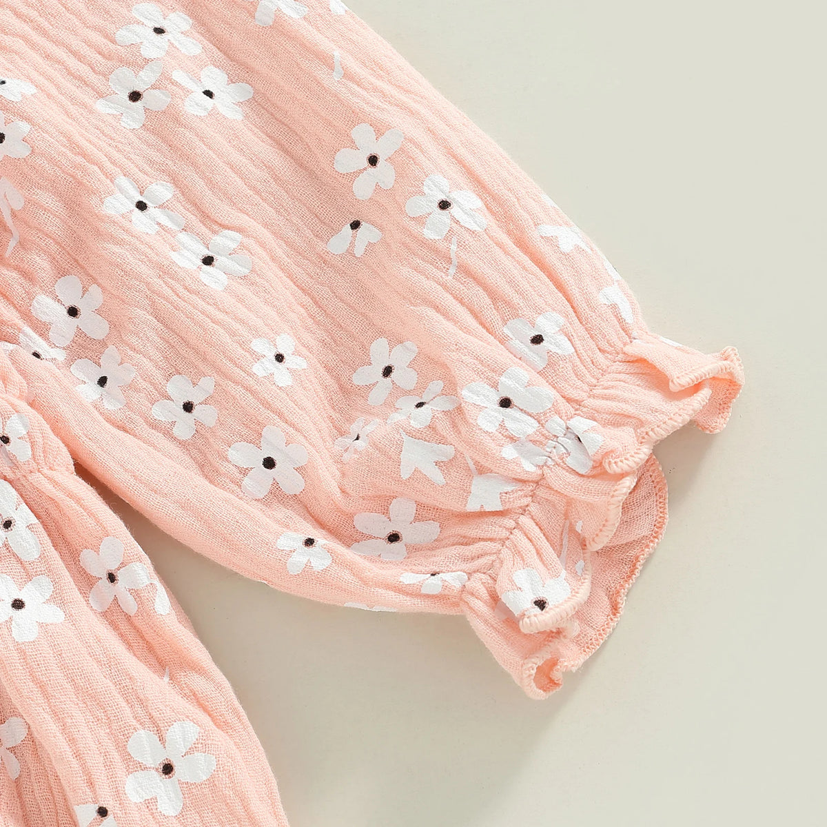 Close-up of pink floral baby romper featuring ruched puff sleeves.