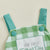Green and white gingham romper for first Father's Day with embroidered patch and button straps.
