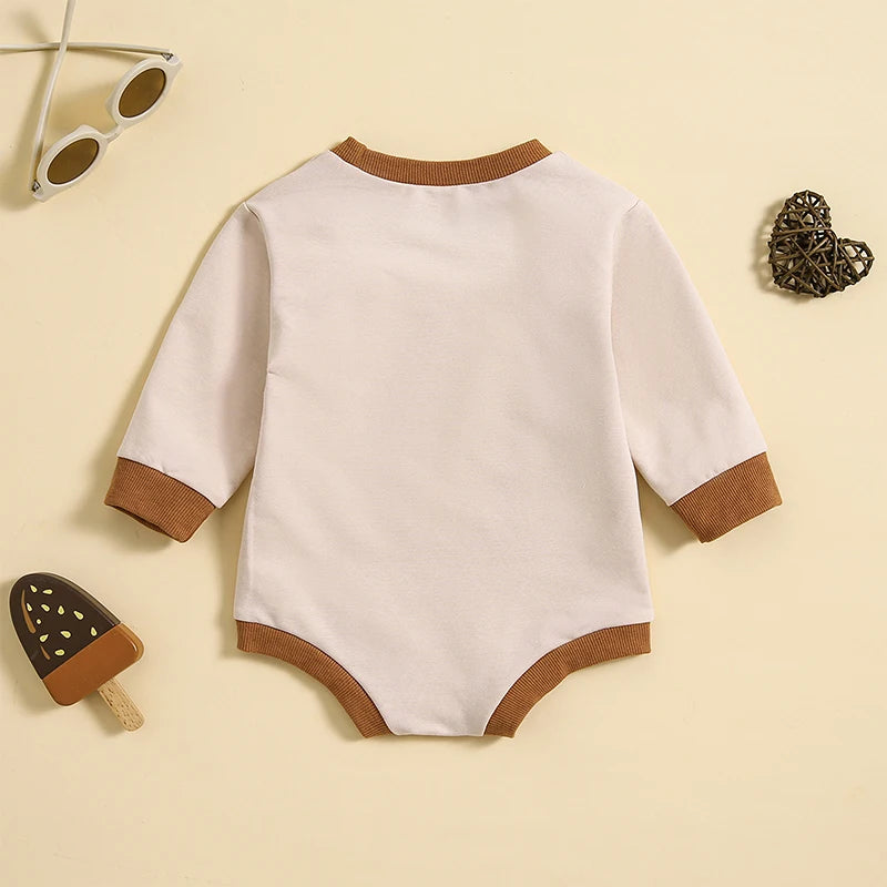 Auntie's Bestie Romper with brown contrast cuffs, suitable for babies 0 to 18 months, on a beige background.