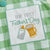 Embroidered patch on gingham romper reading 'Our First Father's Day' with a baby bottle and beer stein design.