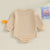 Lil Bro Long Sleeve Romper in soft beige, showcasing the back view with long sleeves and relaxed fit.
