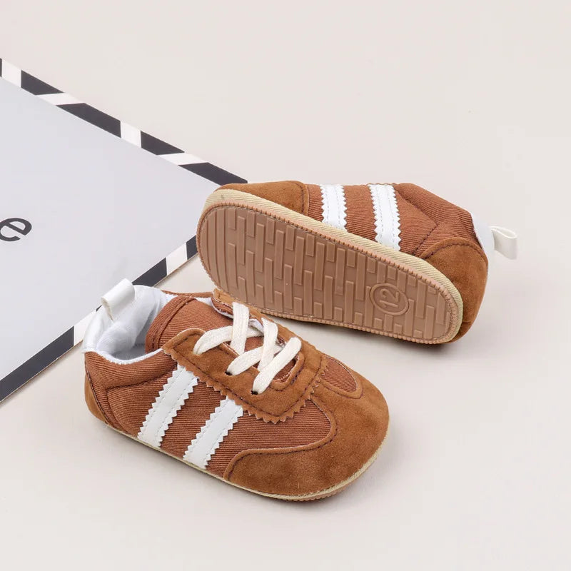 Classic stripe baby sneakers in warm brown with white stripes, perfect for tiny feet aged 0-18 months.