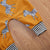 Mustard zebra onesie featuring playful zebra print and striped cuffs, perfect for babies and toddlers.