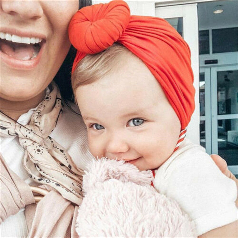 Cute baby girl in a burnt orange top knot turban.