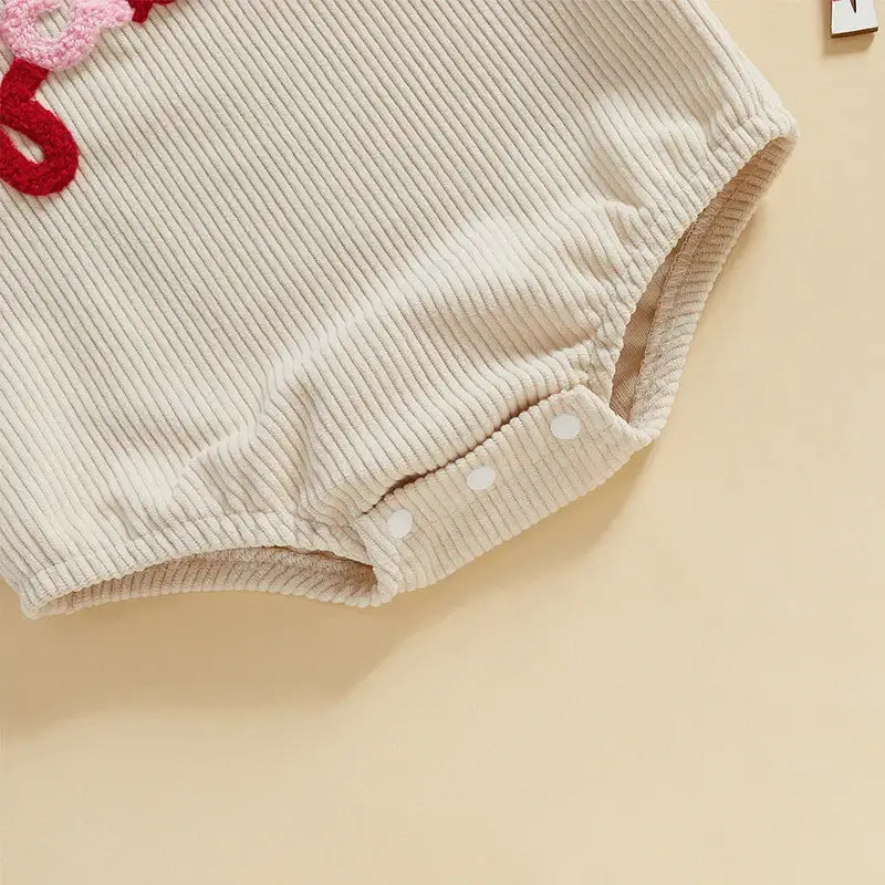 Close-up of Fa La La Christmas romper, featuring soft cream corduroy and playful buttons for easy dressing.