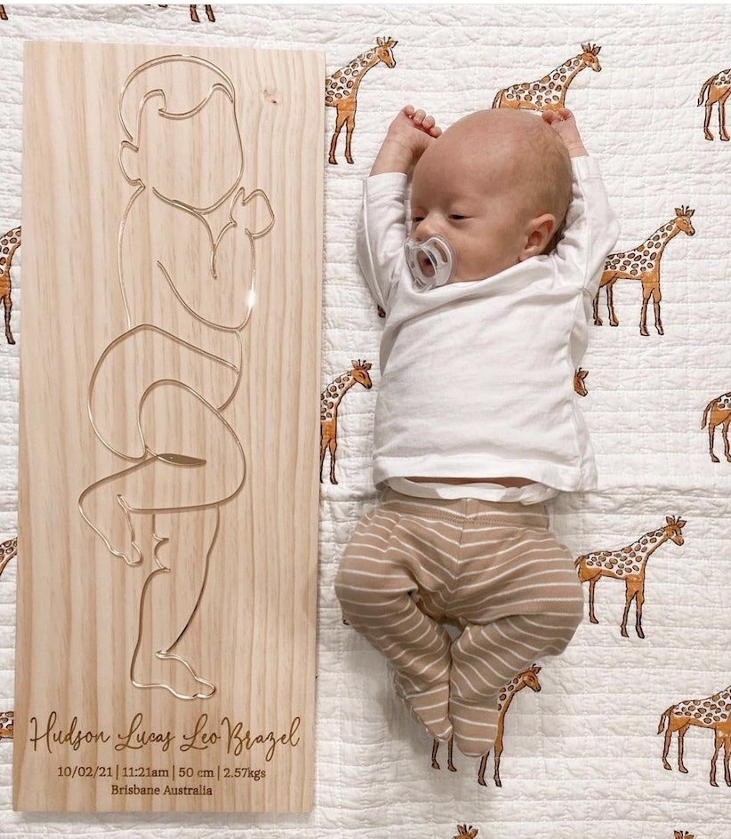 Personalised 3D baby outline birth plaque next to a newborn on a patterned quilt, capturing cherished birth details.