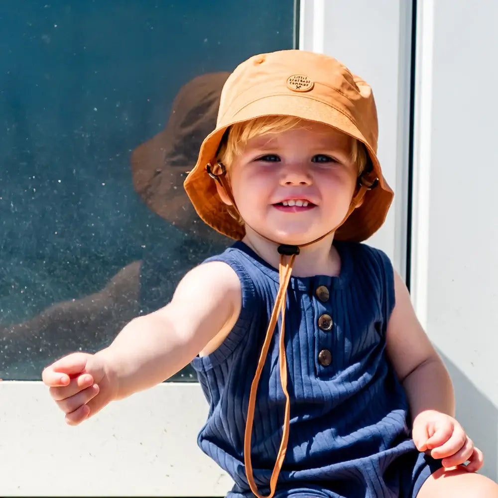 Baby wearing bucket hat with adjustable chin strap in rust