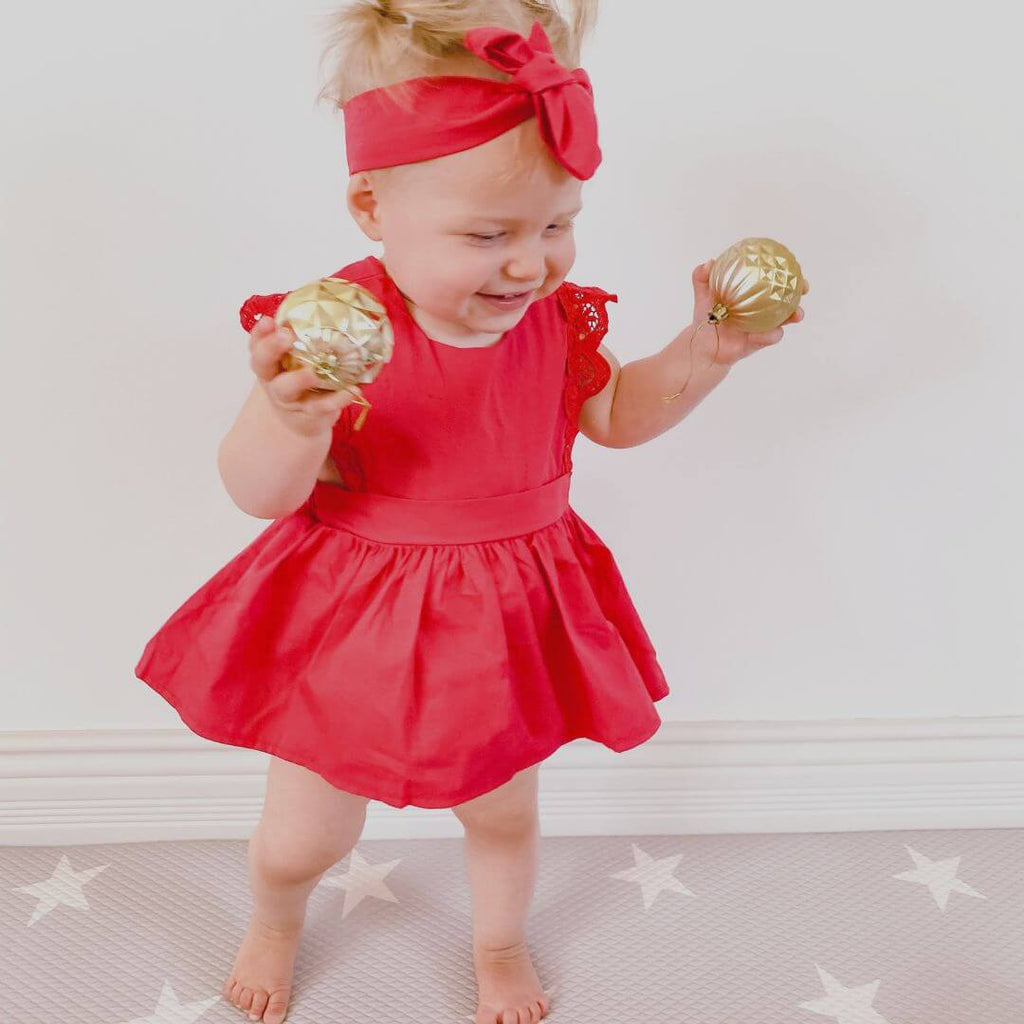 Baby girl in a red dress holding gold Christmas ornaments – Baby Christmas Outfits collection