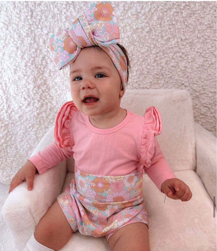 Baby girl wearing pink long sleeve flutter bodysuit