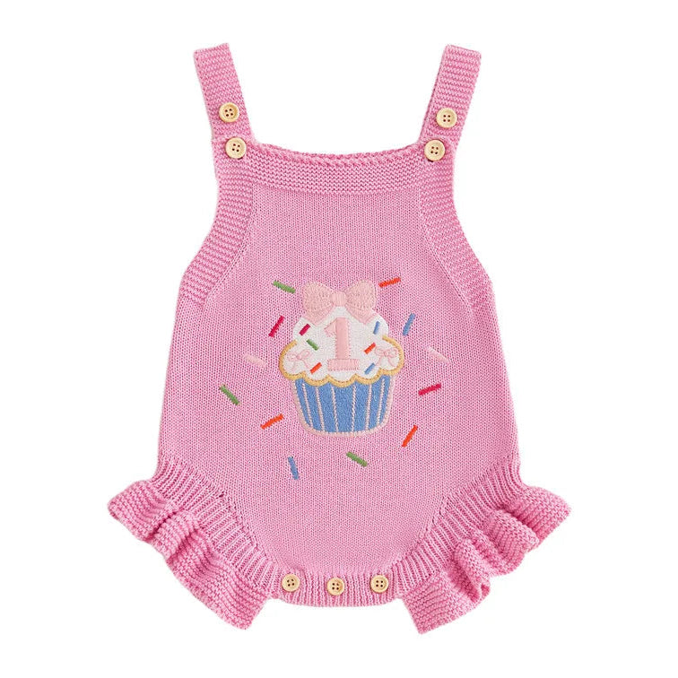 Pink knit first birthday romper with embroidered cupcake sprinkle design, ruffle hem and adjustable button straps